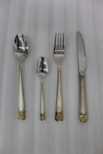 Stainless steel 24-piece cutlery set with gold-bordered handle and embossed flower design on linen napkin