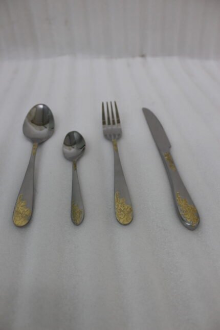 24-piece silver stainless steel cutlery set with gold floral embossed handles displayed on a linen napkin.