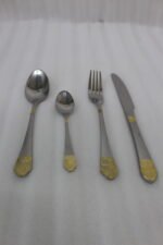 24-piece stainless steel flatware cutlery set with decorative gold handles laid out on a linen cloth
