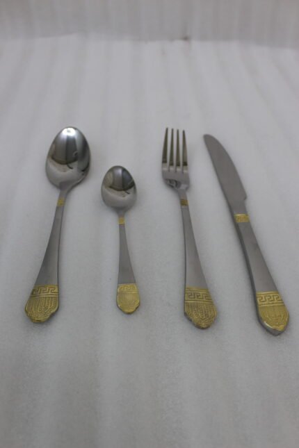 24-piece stainless steel flatware cutlery set with decorative gold handles laid out on a linen cloth