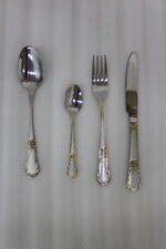 24-piece stainless steel cutlery set with ornate gold embossed handles laid out on a beige linen napkin
