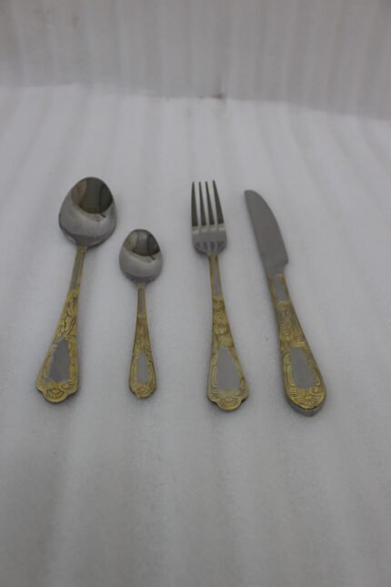 Luxury 24-piece stainless steel cutlery set with ornate gold embossed handles arranged on a linen napkin