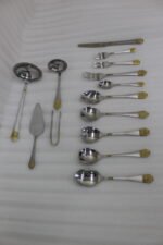 72 piece stainless steel cutlery set with gold detailed handles displayed on a linen mat