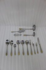 72-piece silver stainless steel cutlery set with embossed gold handles displayed on a linen mat.