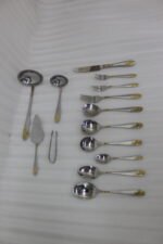 72-piece silver stainless steel cutlery set with embossed gold handles displayed on a linen mat.