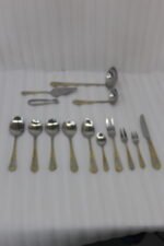72-piece stainless steel cutlery set featuring embossed gold-plated handles laid out on a beige table runner.