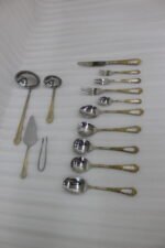 72-piece stainless steel cutlery set featuring embossed gold-plated handles laid out on a beige table runner.