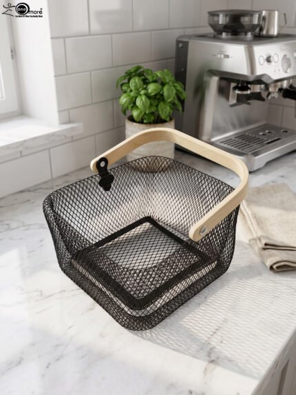 Black double-wall wire mesh storage basket with a wooden top handle sitting on a marble kitchen countertop