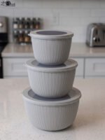 Stack of three light gray ribbed food storage containers with translucent lids on a kitchen countertop
