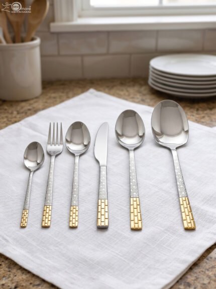 52-piece stainless steel cutlery set with gold accented textured handles arranged on a white cloth