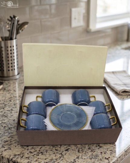 6-piece blue ceramic tea cups with gold handles and matching saucers packaged in a gift box on a kitchen counter