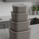 Stacked 4-piece ribbed grey plastic storage box set with fitted lids on a marble kitchen countertop.