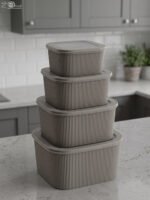 Stacked 4-piece ribbed grey plastic storage box set with fitted lids on a marble kitchen countertop.