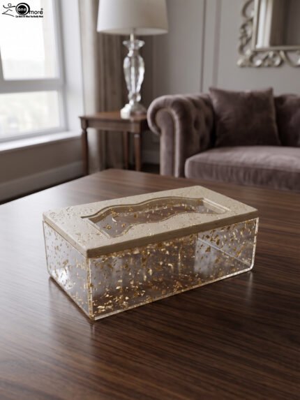 Clear acrylic tissue box holder embedded with gold flakes and a textured beige lid sitting on a wooden table