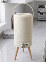 Modern 5L cream beverage dispenser with wooden legs, digital temperature display, and chrome spigot sitting on a marble kitchen countertop.
