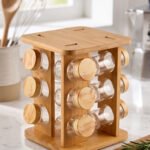 Square wooden bamboo spice rack holding 12 clear glass seasoning jars with wooden lids on a kitchen countertop