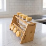 9-piece wooden spice rack with clear glass jars and matching wooden lids displayed on a white marble countertop