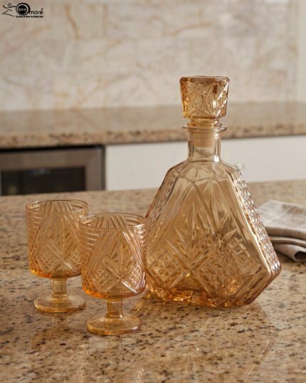Amber crystal glass bottle and matching stemmed glasses set with diamond pattern on a marble table
