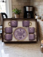 Luxury purple and gold 6-person cup and saucer set neatly arranged in a presentation box on a kitchen counter.