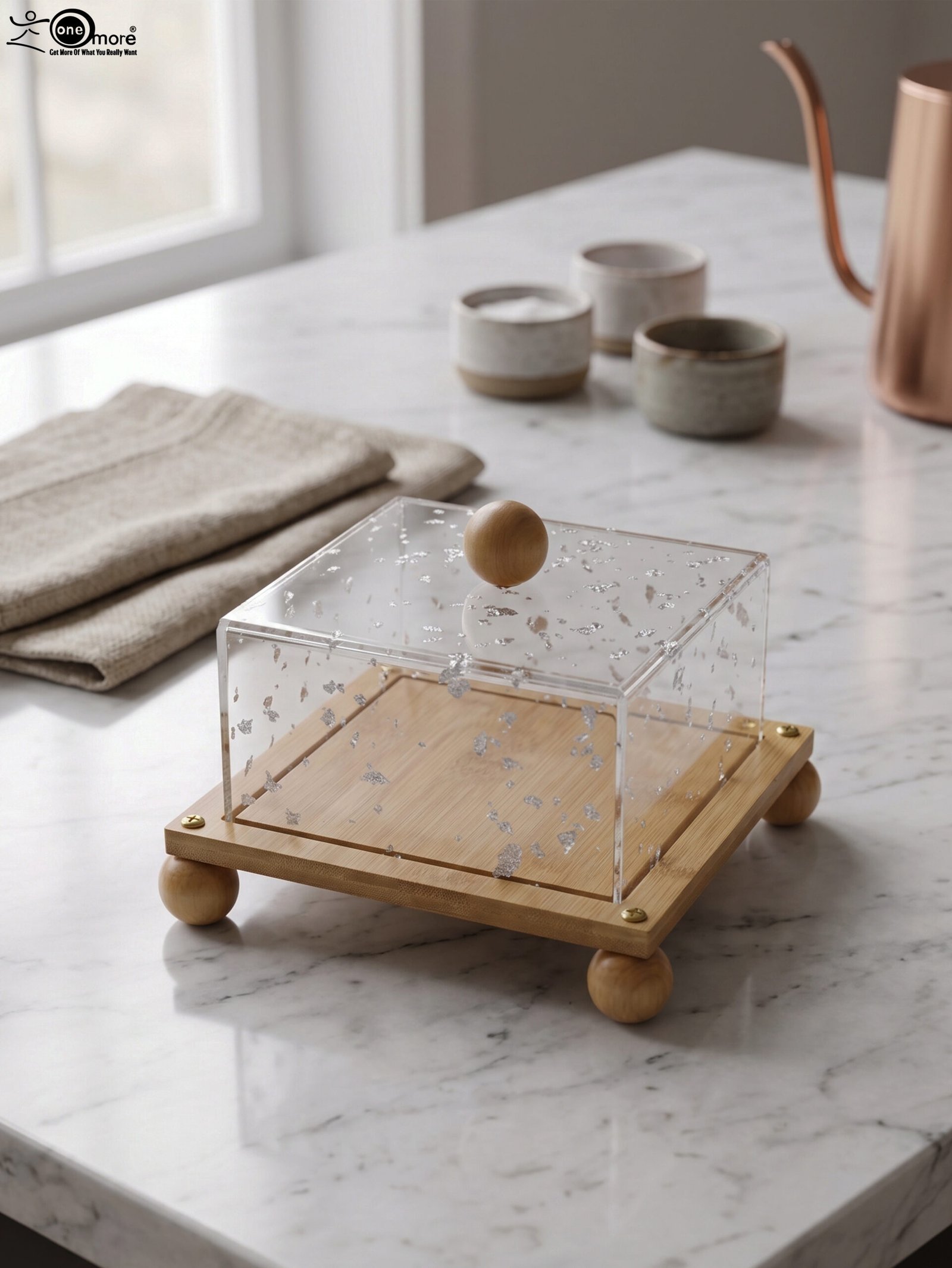 1 Modern square wooden cake dish with a clear acrylic lid featuring embedded silver leaf flakes and round wooden feet on a marble countertop.