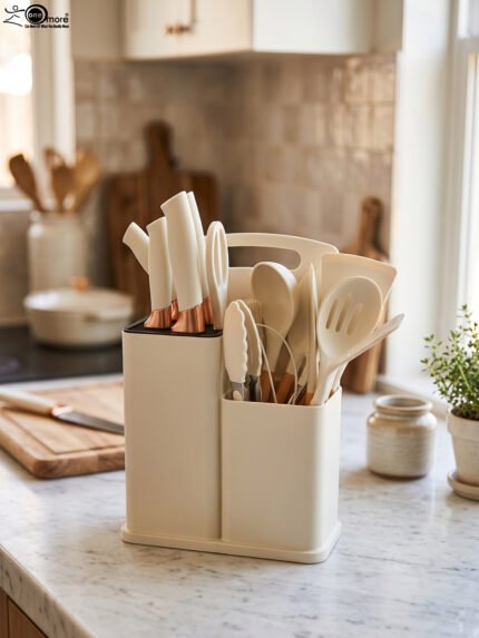 Off-white 19-piece silicone kitchen utensil and knife set with rose gold accents sitting in a dual caddy block on a countertop.