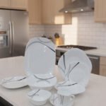 White opal glass dinner set with minimalist black linear wave design displayed on a kitchen island
