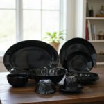 38-piece glossy black opal glass dinner set displayed on a wooden dining table, featuring plates, bowls, cups, and serving dishes.