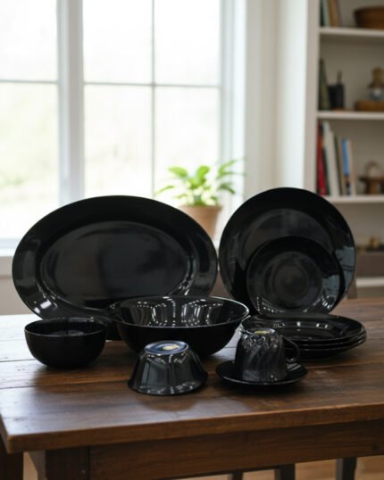 38-piece glossy black opal glass dinner set displayed on a wooden dining table, featuring plates, bowls, cups, and serving dishes.