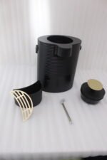 Modern ribbed matte black 2-liter hot water dispenser with gold top button, carrying handle, and gold drip tray on a kitchen countertop.