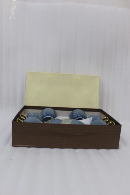 6-piece blue ceramic tea cups with gold handles and matching saucers packaged in a gift box on a kitchen counter
