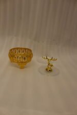 Three clear glass storage jars resting on ornate gold filigree metal stands, each topped with a decorative gold deer figure lid on a white marble kitchen countertop.