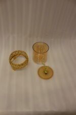 Three amber glass storage jars with gold deer lid handles on intricate gold filigree stands set on a kitchen marble countertop next to an espresso machine.