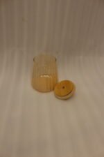 Three ribbed amber glass storage canisters with wooden lids and crystal knobs sitting on a marble kitchen countertop.