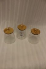Three ribbed glass storage jars with natural wooden lids topped with clear crystal diamond knobs on a kitchen countertop.