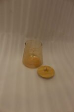 Three amber textured glass storage jars with natural wooden lids and crystal crystal-cut handles sitting on a marble kitchen countertop.