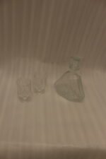 Crystal glass water bottle decanter with stopper alongside matching patterned stemmed glasses on a kitchen counter.