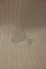 Crystal glass water bottle decanter with stopper alongside matching patterned stemmed glasses on a kitchen counter.