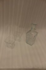 Clear crystal glass decanter bottle and matching tumbler drinking glasses with diamond pattern on kitchen counter