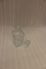 Clear crystal glass decanter bottle and matching tumbler drinking glasses with diamond pattern on kitchen counter