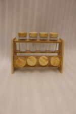9-piece wooden spice rack with clear glass jars and matching wooden lids displayed on a white marble countertop