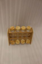 9-piece wooden spice rack with clear glass jars and matching wooden lids displayed on a white marble countertop