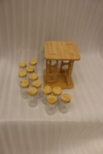 Square wooden bamboo spice rack holding 12 clear glass seasoning jars with wooden lids on a kitchen countertop