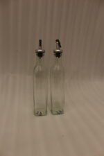 2 Pcs transparent glass oil dispenser bottles with stainless steel leak-proof pour spouts set on a marble kitchen counter