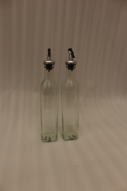 2 Pcs transparent glass oil dispenser bottles with stainless steel leak-proof pour spouts set on a marble kitchen counter