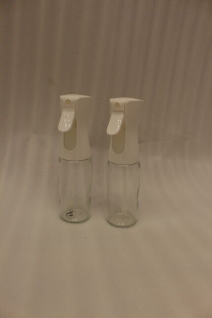 2 Pcs clear glass oil sprayer bottle set with ergonomic white trigger nozzles on a kitchen countertop