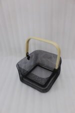 Black double-wall wire mesh storage basket with a wooden top handle sitting on a marble kitchen countertop