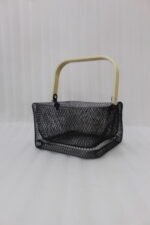 Black double-wall wire mesh storage basket with a wooden top handle sitting on a marble kitchen countertop