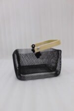 Black double-wall wire mesh storage basket with a wooden top handle sitting on a marble kitchen countertop