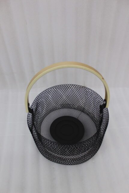 Black double-wall wire mesh fruit basket with a curved wooden handle sitting on a gray kitchen countertop.