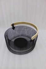 Black double-wall wire mesh fruit basket with a curved wooden handle sitting on a gray kitchen countertop.